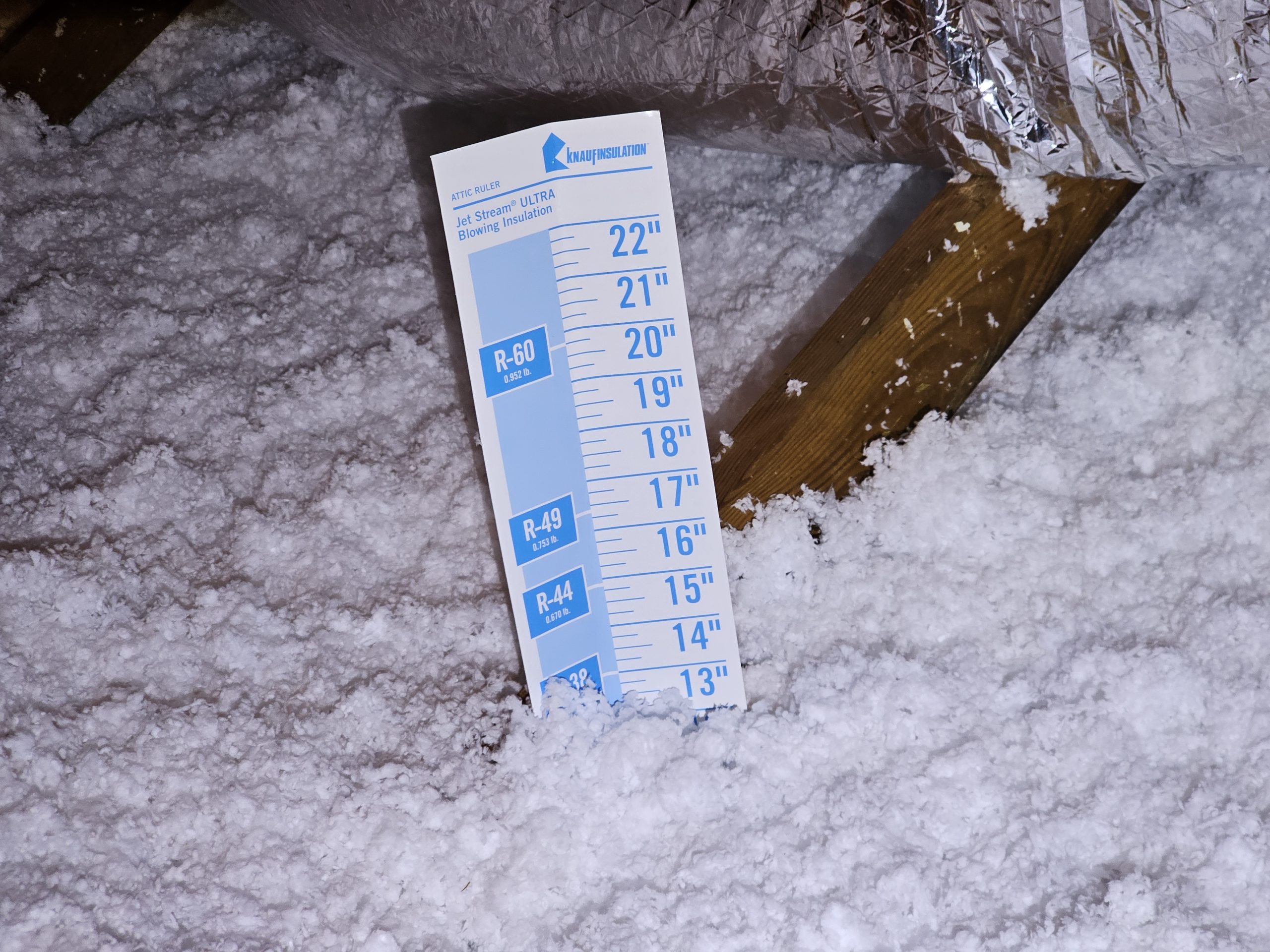 Blow In Attic Insulation, image of blow in insulation with measuring stick to ensure proper R value
